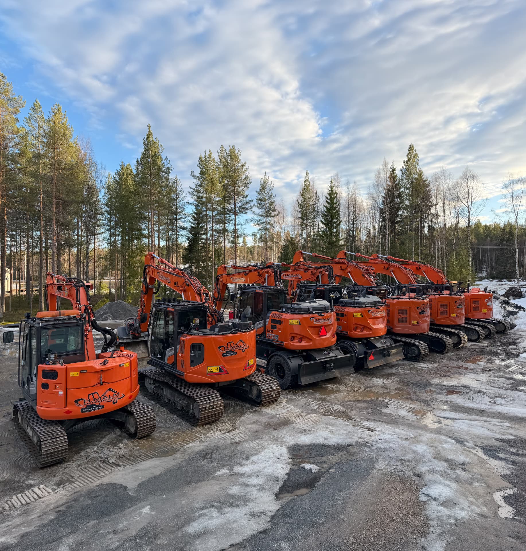 H.Malm Entreprenads maskinpark med orange grävmaskiner i Skellefteå