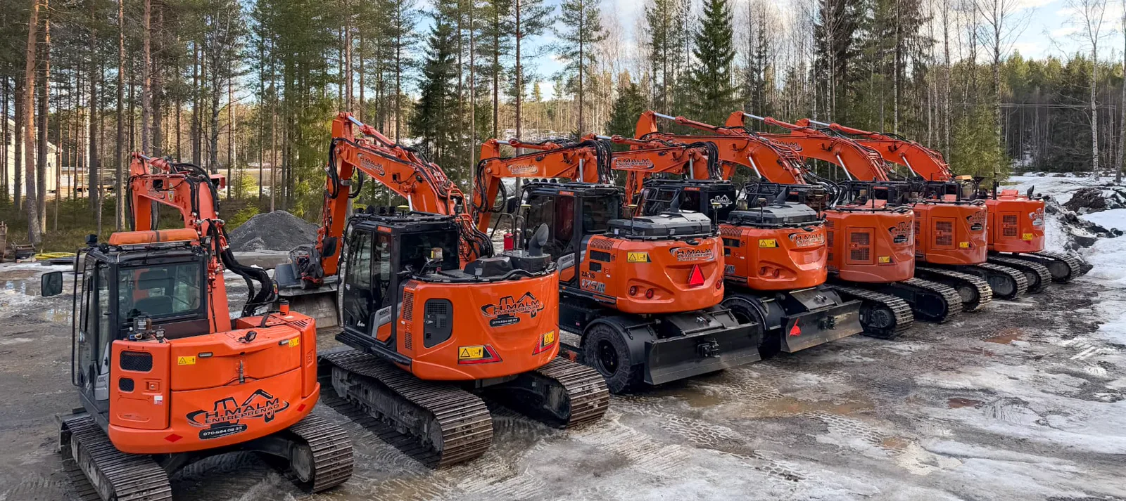 H.Malm Entreprenads maskinpark med orange grävmaskiner i Skellefteå